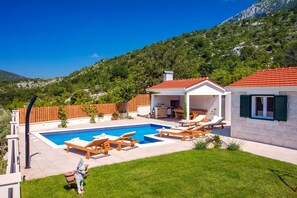Pool area with 6 sunbeds and an outside kitchen and dining area