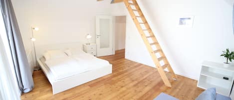 Luftig: Schlafzimmer mit hohen Decken und Holzbalkenkonstruktion.