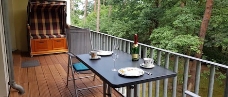 Balkon mit Strandkorb und Blick in den Küstenwald