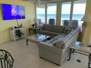 Living room has a 65” smart TV with cable and HBO; leather sofa and ocean view.