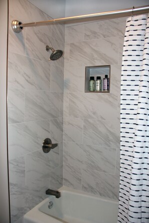 Marble shower in bathroom with boutique hair and bath products