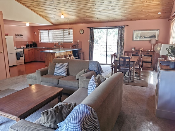 Living area with couches,  games cabinet and dining table . Kitchen on left.