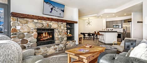 Warm living area with wood burning fireplace, flat screen TV and access to the deck.