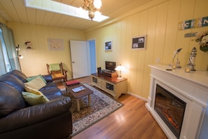 Living room with skylight, cozy fireplace, comfy seating, books and games