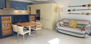 Living room with a sofa, dining table, TV and auxiliary table. Open kitchen, equipped with all its necessary tools.