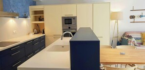 Living room with a sofa, dining table, TV and auxiliary table. Open kitchen, equipped with all its necessary tools.