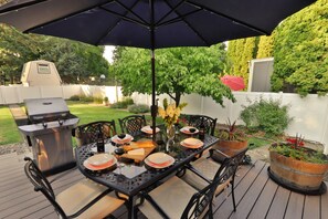 Deck dining table, umbrella, and BBQ.