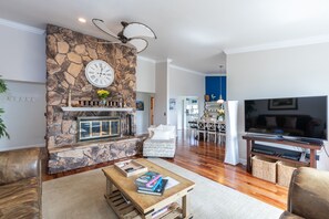 The seating in the open living room surrounds a large fireplace center piece.