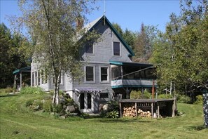 The back of the house captures a view of the screened porch and wood fired tub