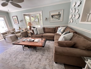 Ample seating to visit or watch TV w/ 2 chairs and a sectional w/ view of pool