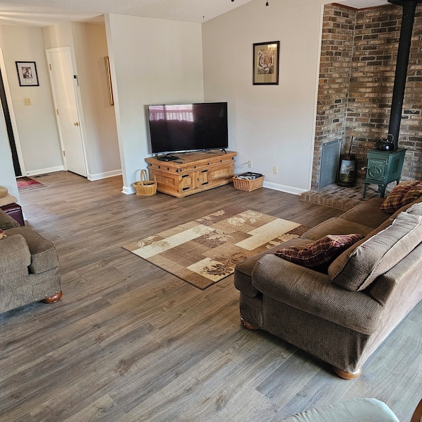 Living room with big screen TV, couch, love seat and glider chair.