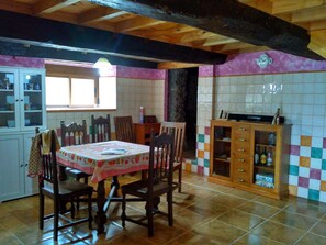 Vista de la cocina, con mesa de castaño. Al fondo acceso a bodega y la nevera