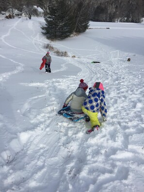 great sledding on back hill, with farmhouse in background
