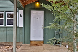 The front porch and one of the pretend  shutters adorned by a fir tree cutout.