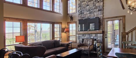 Cozy living room with beautiful floor to ceiling windows and cus - Cozy living room with beautiful floor to ceiling windows and custom stone fireplace