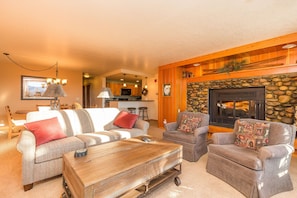 Living area with wood burning fireplace, flat screen TV, ample seating and access to the private balcony.