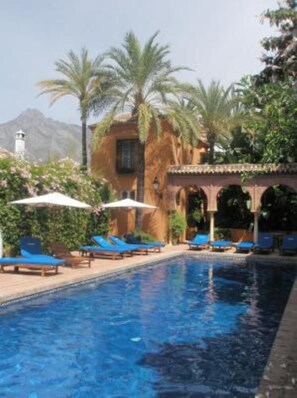Resort pool, heated in winter, with confortable loungers and sun parasols.