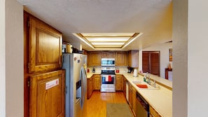 Kitchen with full size refrigerator, glass top stove, oven and microwave.  