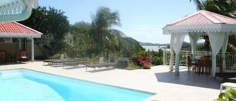 vu du salon sur la piscine la terrasse et la vue panoramique donnant sur la mer