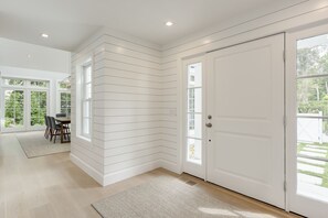 Light stain floors, paneled walls, and spot lighting mark the entry hall. 