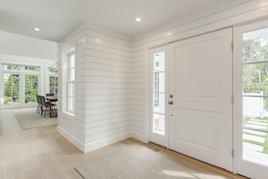 Light stain floors, paneled walls, and spot lighting mark the entry hall. 