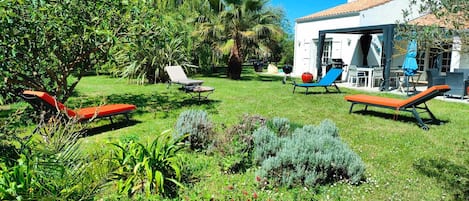 La terrasse sud avec sa pergola et les quatre bains de soleil sur la pelouse sud