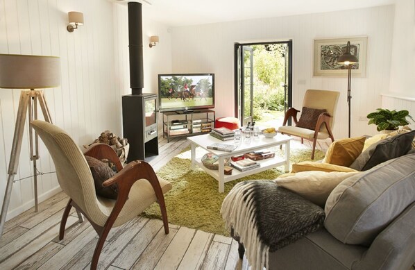 The Dairy, Cotswolds: Sitting room with a contemporary wood burning stove and views out to the garden