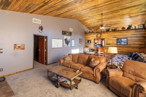 Large livingroom with vaulted ceilings, love seat, couch and recliner.