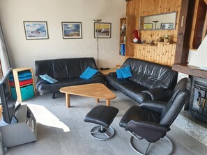 Wohnzimmer mit Ledermöbel, TV und Kaminofen und Panoramablick