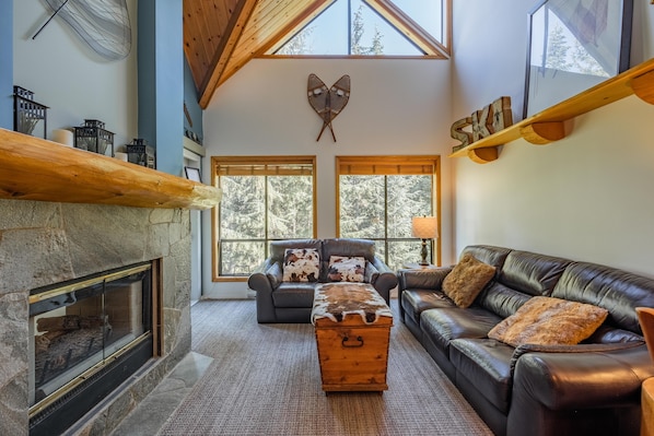 Spacious living area with high ceiling, gas fireplace, and smart TV.