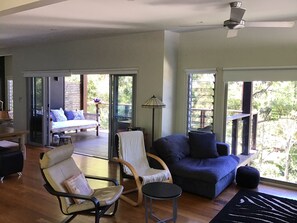 Living spaces open to large  upper deck with daybed and inside or outside dining