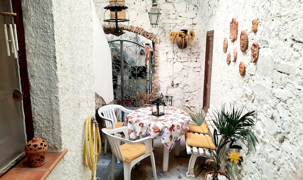 Cortile attrezzato, circondato dalle case in pietra, vista su vicolo pedonale.