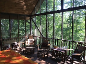 Screened porch on the main level with a picnic table and seating area.