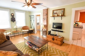 Living room with seating and TV leading into kitchen area