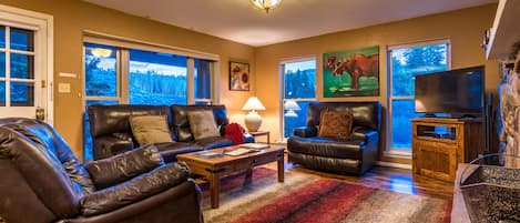 Living room features lots of natural light, views of the river and fireplace.