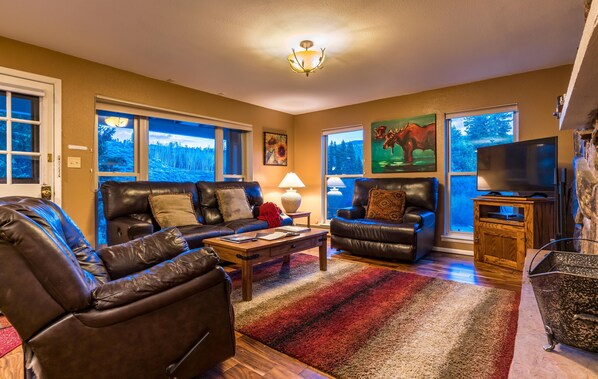 Living room features lots of natural light, views of the river and fireplace.