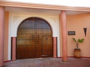 EntrĂ©e principale avec un immense portail marocain en bois de chĂȘne cloutĂ©.