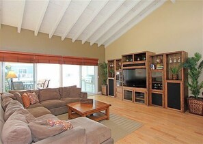 Large living room with flat screen and natural light from patio.