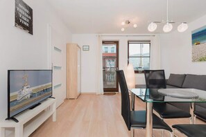 Stylish living room with television, dining table with chairs, kitchenette and double sofa bed.