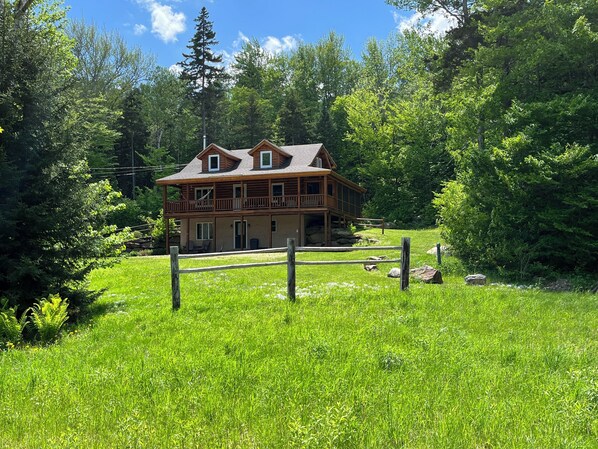 Mountainside cabin surrounded by forest and streams.