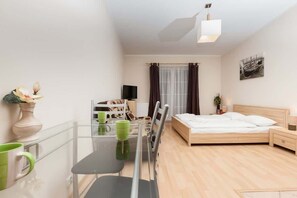 Stylish and elegant living area with cable television, dining table with chairs, bed for two people and functional cabinets.