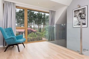 A peaceful sitting area by a large window, furnished with a light blue armchair, offering a relaxing spot to enjoy the view of the garden.