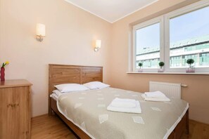 A bedroom featuring a double bed with light bedding, bedside tables, and large windows that bring in natural light, creating a warm, inviting atmosphere.