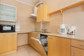 A compact kitchen with wooden cabinets, a microwave, electric kettle, and other small appliances on the countertops. The layout is efficient, providing ample storage space.