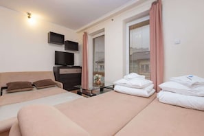 Another angle of the living room with a view of the couch and a folded set of towels placed on the bed in the background. It emphasizes the comfort of the space, blending the bedroom and living area.