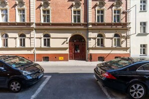 A street scene outside the building, showing parked cars and historic buildings with classic European architectural details.