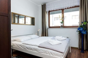 A cosy bedroom with a double bed over which hangs a mirror.