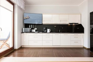 The bright space and functionality of the kitchenette, with its white furniture, allows you to enjoy meals in front of the flat-screen TV.