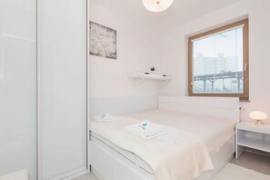 White bedroom with comfortable double bed and capacious wardrobe, where the guests can store their clothes.