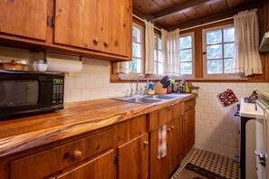 Rustic kitchen with stocked pans, dishes, glassware, flatware and cookware